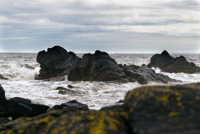 Rocks in sea against sky