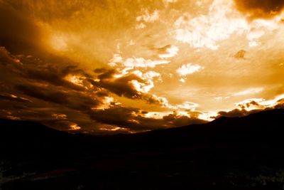 Scenic view of mountains against cloudy sky at sunset
