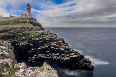 Scenic view of sea by cliff against sky