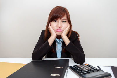 Portrait of young woman using phone while sitting on table