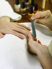 Cropped hands of woman doing manicure of female customer in spa