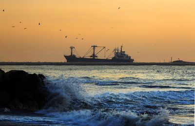 Silhouette ship in sea against sky during sunset