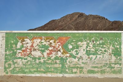 Close-up of text on mountain against blue sky