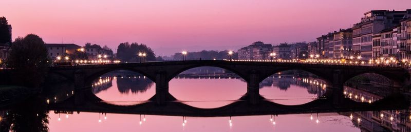 Arch bridge over river against sky at night