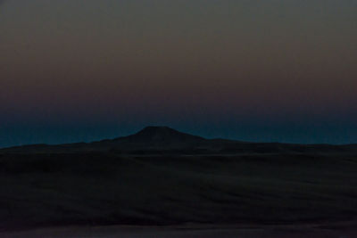 Scenic view of desert against sky at sunset