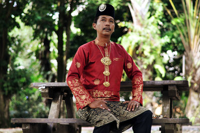 Man in traditional cloth sitting on picnic table in park