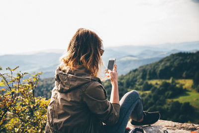 Rear view of woman standing on mountain against sky