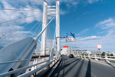 White cable bridge over road in city against sky