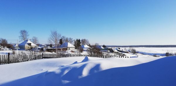 Snow covered buildings against clear blue sky