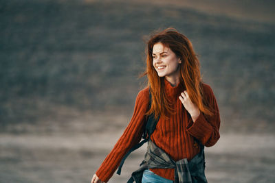 Portrait of smiling young woman standing against sea