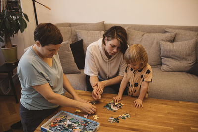 Mothers and daughter solving jigsaw puzzle