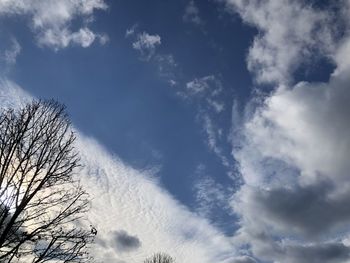 Low angle view of bare tree against cloudy sky