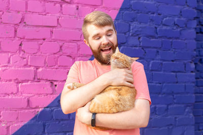 Portrait of a smiling young man holding the wall