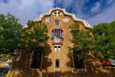 Low angle view of trees and building against sky