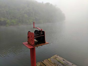 Lifeguard hut in lake against sky during foggy weather