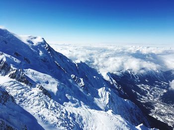 Scenic view of snowcapped mountains against blue sky