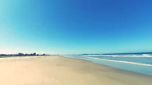 Scenic view of beach against clear blue sky