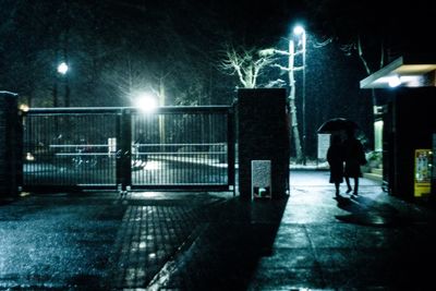 Woman walking on illuminated street at night