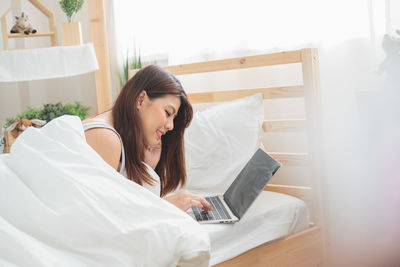 Young woman using mobile phone on bed