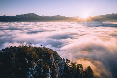 High angle view of man standing on mountain ridge rising above the clouds, hallein, austria