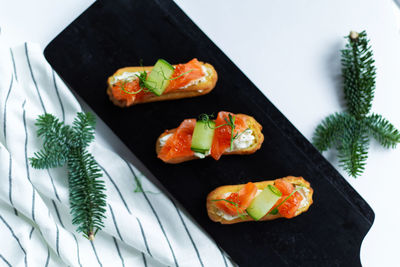 Eclairs with salmon, fresh vegetables and herbs, gourmet snacks.