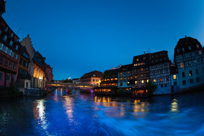 Canal amidst buildings against blue sky at dusk