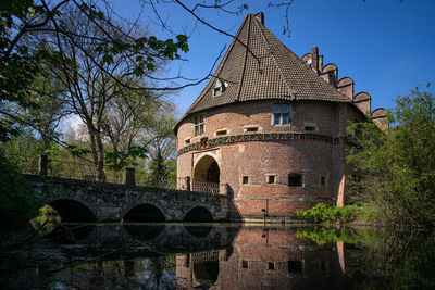 Arch bridge over river by building against sky