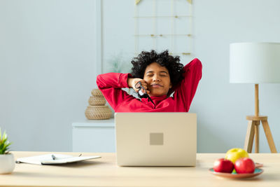 Young woman using laptop while sitting on table