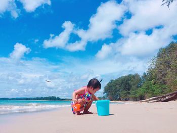 Girl playing at beach against sky