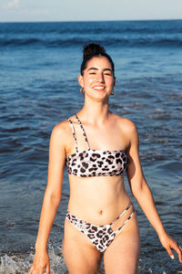 Portrait of woman in bikini standing at beach