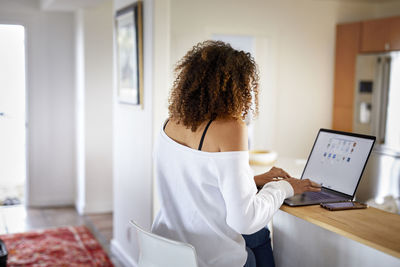 Rear view of woman using laptop computer while sitting at home