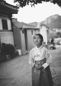 Girl standing on road against houses