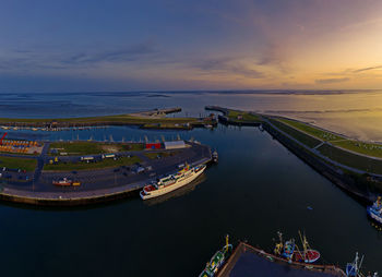 High angle view of harbor by sea against sky during sunset