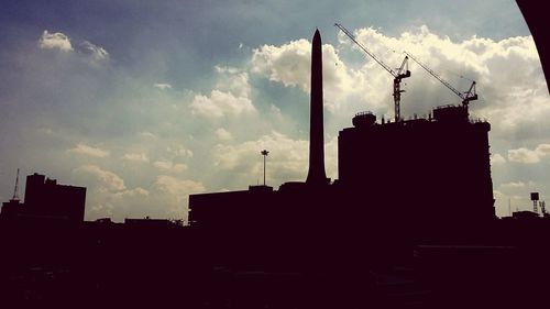 Low angle view of silhouette buildings against cloudy sky