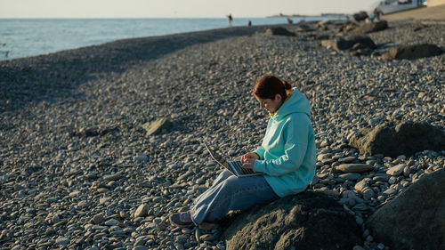 Side view of man sitting at beach