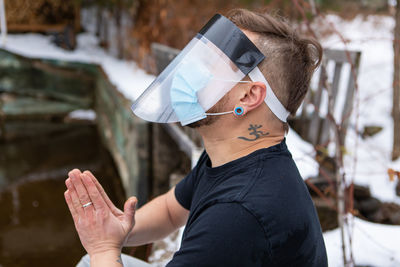 Side view of man wearing face shield praying outdoors