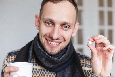 Portrait of man holding cup and medicine