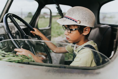 Boy driving while sitting in car