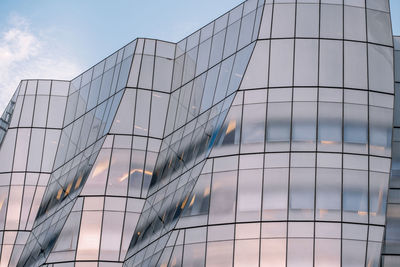 Low angle view of modern glass building against sky