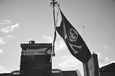 Low angle view of flags on building against sky