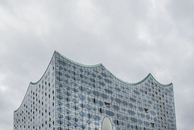 Low angle view of modern building against cloudy sky