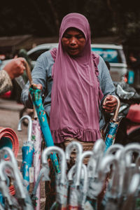 Female vendor selling umbrellas on road in city