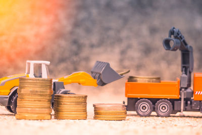 Close-up of coins stacked against toy bulldozers