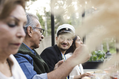 Family sitting at dining table while enjoying dinner party in patio