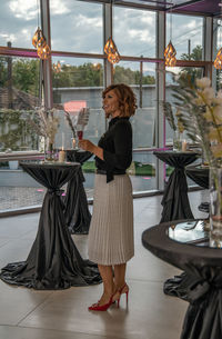 Side view of woman standing by glass window