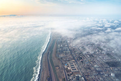 Aerial view of city by sea against sky