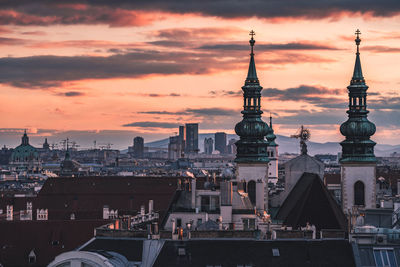 View of church amidst buildings against sky in city at sunset