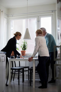 Full length of estate agent explaining documents of new house to senior couple