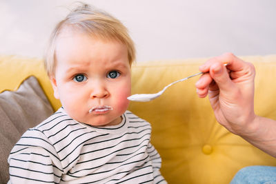 Mom feeds a small child at home with yogurt from a spoon. family concept