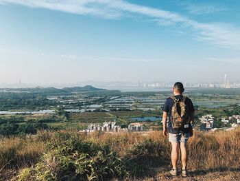 Full length of man looking at cityscape against sky